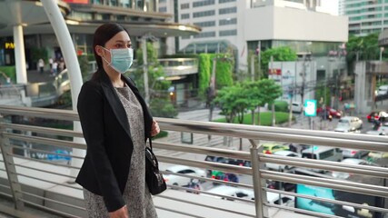 Wall Mural - slow-motion of business woman walking and wearing medical mask for protection from coronavirus (covid-19) pandemic in the city