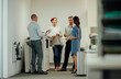 © Aila Images/Stocksy - Young diverse business people interacting next to office photocopier