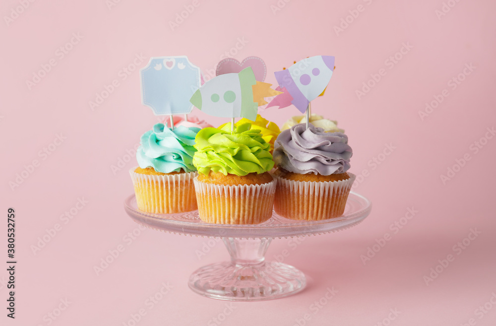 Tasty cupcakes with stylish toppers on color background