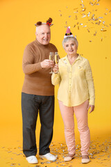 Wall Mural - Elderly couple with champagne celebrating Christmas on color background