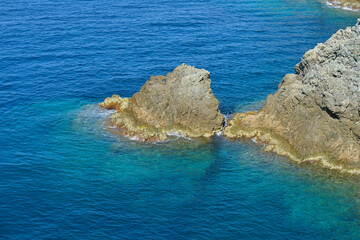 Clear amazing azure colour sea water with granite rocks in beach, Italy. Aerial view of sea waves and fantastic Rocky coast, Italy. Rock and sea. Stone rock close up in the sea water.