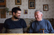 © Jovana Milanko/Stocksy - Grandpa and his grandson sitting at the table talking and laughing