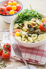 Arugul And Pasta Salad With Cherry Tomatoes And Black Olives With Pesto And Pumpkin Seeds