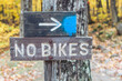 © Mihael Blikshteyn Photography/Stocksy - No Bikes'' sign with an arrow and blue dot on a tree next to a hiking trail