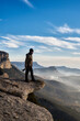 © Guille Faingold/Stocksy - Photographer standing on the edge of a cliff with his camera looking down
