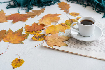 there are autumn leaves on the table, next to it is a mug of coffee and a newspaper