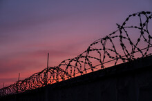 Silhouette Of Barbed Wire Against Sunset Sky