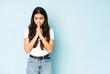 © Asier - Young indian woman on blue background praying, showing devotion, religious person looking for divine inspiration.