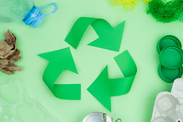 Recycling logo on green background with objects to recycle.