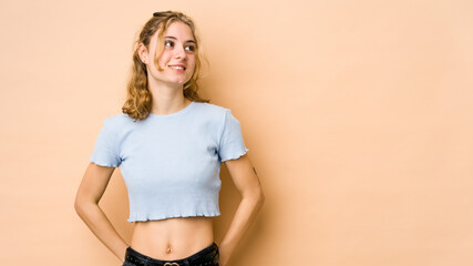 Wall Mural - Young caucasian woman isolated on beige background relaxed and happy laughing, neck stretched showing teeth.