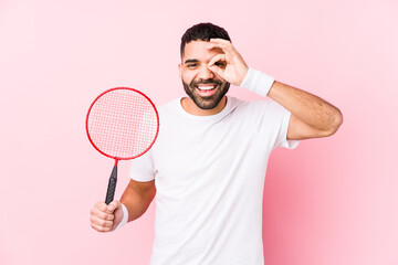 Wall Mural - Young arabian man playing badminton isolated excited keeping ok gesture on eye.