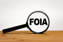 Focused on business concept. Magnifier glass with word FOIA Freedom of Information Act on wooden table. Business concept. Search idea