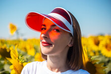 Young Woman In Red Sun Visor And White T-shirt On Sunflower Field