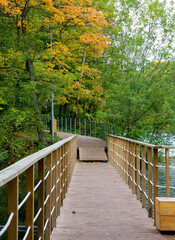 Fototapete - Boardwalk across the lake in autumn park