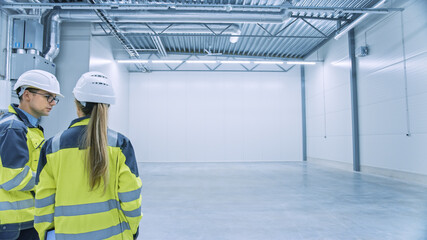 Poster - Two Engineers Talking, Standing in the Middle of an Empty Warehouse, Inspecting, Planning Future Factory Layout. Professionals Industrial Designers Strategizing about New Manufacturing Plant Design.