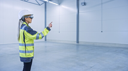 Poster - Industry 4.0 Modern Factory: Female Engineer in Empty Warehouse Wearing Augmented Reality Headset and Working in Mixed Reality Software with Gestures. Great Mock-up Template for VFX Special Effects.
