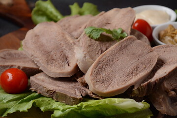 Wall Mural - Sliced Beef Tongue Slices on a platter with lettuce leaves, cherry tomatoes and Dijon mustard on a wooden background