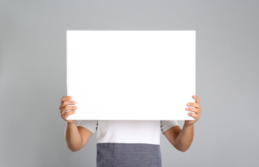 Wall Mural - Man holding white blank poster on grey background. Mockup for design