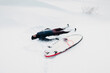 Cold winter and male surfer relax on beach with surfboard. Winter day with surfer in wetsuit.