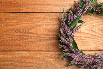 Beautiful autumnal wreath with heather flowers on wooden background, top view. Space for text