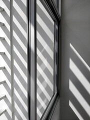 Wall Mural - Selective focus at glass window sill, side view and diagonal pattern of sunlight and shadow shining through from outside of building in black and white style