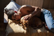 © Demetr White/Stocksy - a guy with no legs at home lies on a bed with a dog