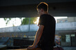 © Demetr White/Stocksy - photo of a guy in a black T-shirt with backlight against a skatepark