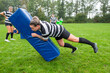 © Ivo de Bruijn/Stocksy - A female rugby player is tackling the tackle bag hard during pra