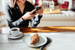 © Bonninstudio/Stocksy - Crop businesswoman browsing smartphone in coffeehouse