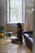 © VeaVea/Stocksy - Woman sitting on a floor of a living room, drinking coffee