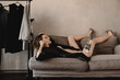 © Alina Hvostikova/Stocksy - Model with broken leg speaking on smartphone on sofa