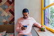 © MyMicrostock/Stocksy - Happy man using phone in cafe