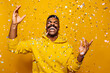 © MyMicrostock/Stocksy - Happy african american man over yellow background with confetti falling on head