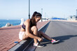 © Guille Faingold/Stocksy - Jogger tying shoelaces on seaside promenade