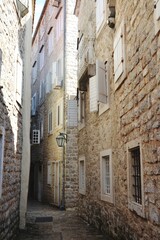  Narrow street and a brick wall buildings in old town od Budva, Montenegro