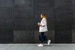 © MyMicrostock/Stocksy - Happy trendy businesswoman walking besides a black wall