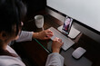 © MyMicrostock/Stocksy - Anonymous woman working at home during a video call at night in