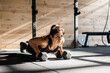 © Sergio Marcos/Stocksy - Woman doing push ups in a crossfit box