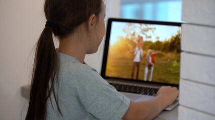 Wall Mural - little girl looking at a photo in a laptop