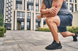 © IC Production - Closeup muscular man’s leg and arm in sneakers and shorts during warm-up outdoors. Sport concept