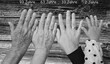Schwarz-Weißaufnahme von vier Hände im Alter von jeweils 93 Jahren, 63 Jahren, 33 Jahren und 2 Jahren vor einem Hintergrund mit Holzstruktur und Altersangaben in Textform