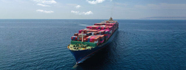 Aerial drone panoramic ultra wide photo of industrial container tanker ship loaded with colourful truck size containers cruising open ocean deep blue sea