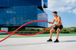 © Manuel Ruiz Alba/ADDICTIVE STOCK - Side view of muscular male athlete with naked torso doing exercises with battle ropes on terrace during sunny day in summer