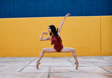 Flexible Female Ballet Dancer Performing In City Near Vibrant Building While Balancing On Tiptoes In Pointe Shoes
