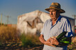 © Si And Si/ADDICTIVE STOCK - Elderly male farmer in straw hat carrying pile of ripe green zucchini while harvesting vegetables in agricultural field in summer day