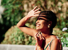 Side View Of Cheerful Young African American Female Covering Eyes From Sunlight While Spending Summer Day In Green Park