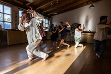 Full Body Of Mature Male Instructor With Group Of Diverse People Performing Chi Kung Pose During Practice In Studio