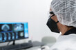 © Javier Ballester/ADDICTIVE STOCK - Side view of female medical specialist in protective mask and goggles working with scan image on computer monitor in modern clinic