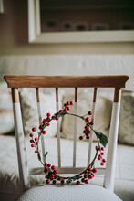Simple Wreath Made With Decorative Red Berries Placed On Chair In Cozy Room During Christmas Preparation
