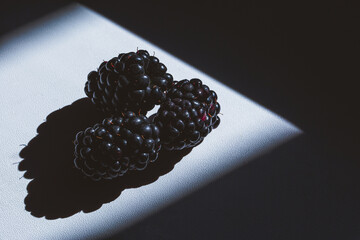 Cutted Fresh blackberry with shadows on dark and white background. contrast shadow fruitf lat lay, top view. Copy space